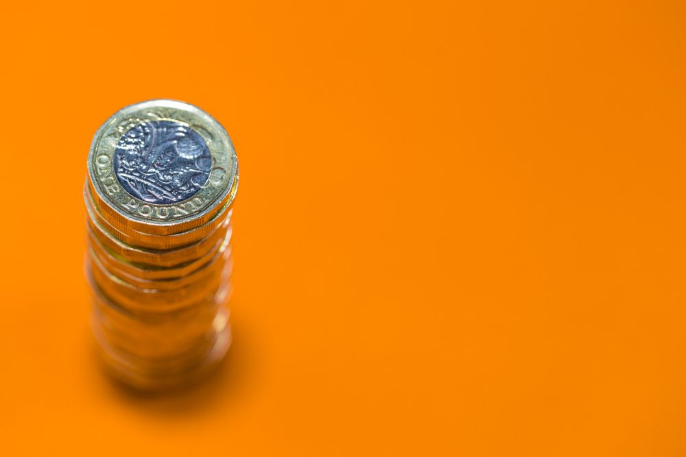 A pile of pound coins on an orange background