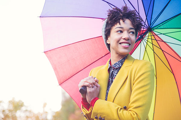 Young woman smiling under a colourful umbrella