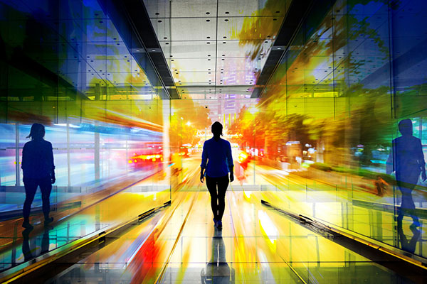 A woman walking towards colourful lights at the end of the tunnel