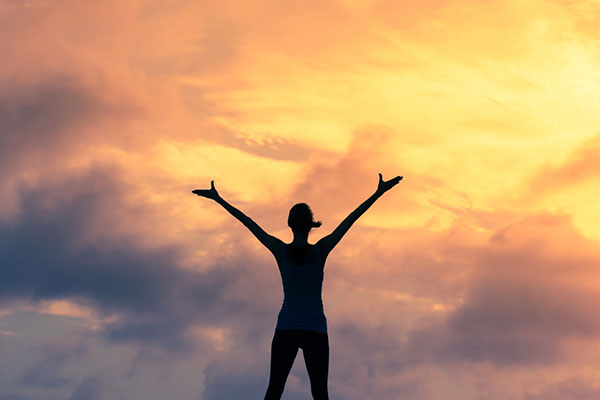 Woman with arms outstretched against sunset