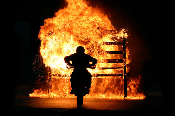 A motorbike in front of a wall of fire