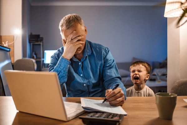 stressed-man-with-his-two-years-old-son-working-from-home-picture