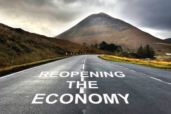 Road with the words reopening the economy and mountain backdrop. 
