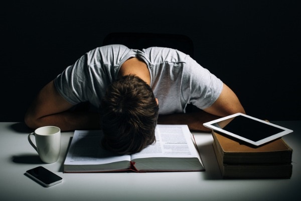 Man with head slumped in a book. 