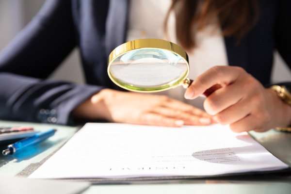 businesswoman-looking-at-contract-form-through-magnifying-glass