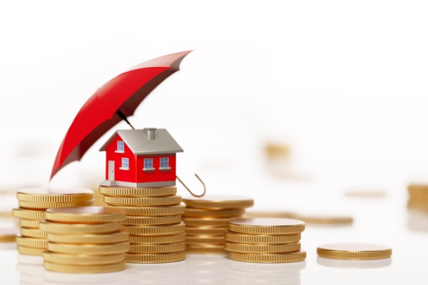red-toy-house-sitting-on-white-background-behind-coin-stack-insurance