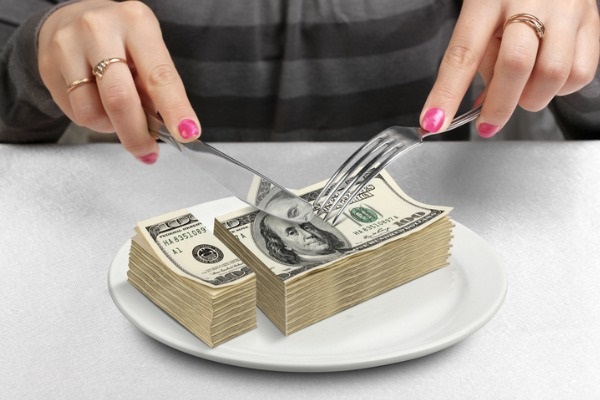Hands cut money on plate reduce funds concept picture. 
