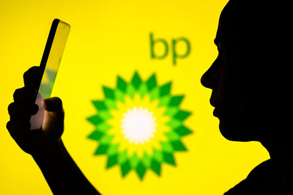 BP logo in background, investor on a smartphone in the foreground 600