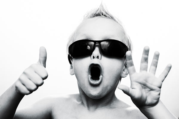 A child in sunglasses holding up six fingers