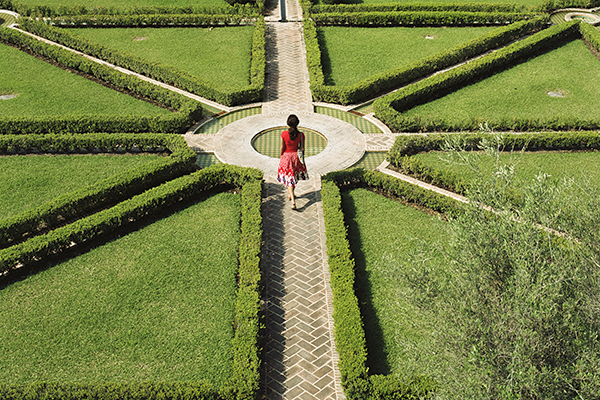 A woman in a formal garden trying to choose a path
