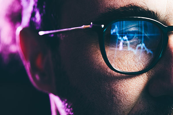 Close-up view of an investor's face with stock chart reflected in his glasses 600
