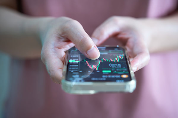 Woman trading stocks online on mobile phone