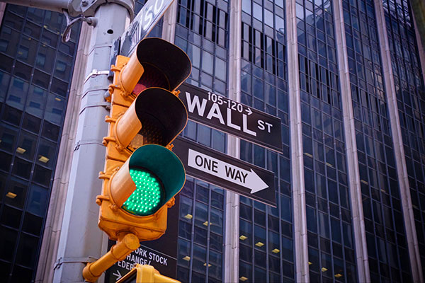 Wall St sign, skyscraper, and green traffic light