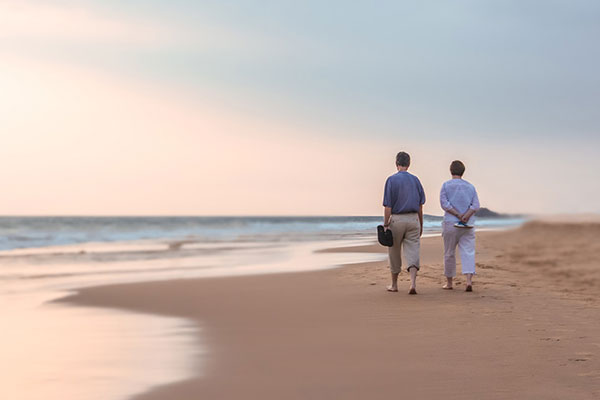 abrdn retired couple walking on a beach