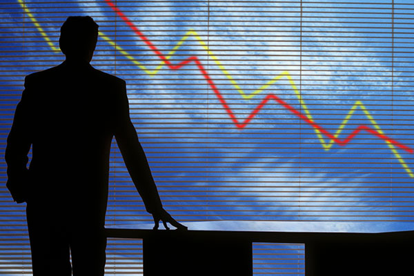 The winding down of a business represented by silhouetted man in empty office against downward arrows