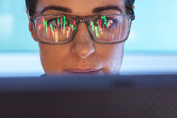 Woman analysing stock market with reflection on glasses Getty