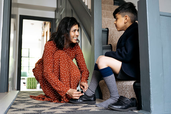 Mother helping schoolboy with shoes