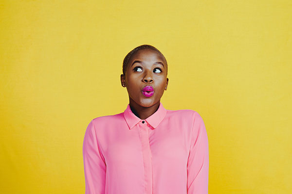 Young woman looking curious against a yellow background