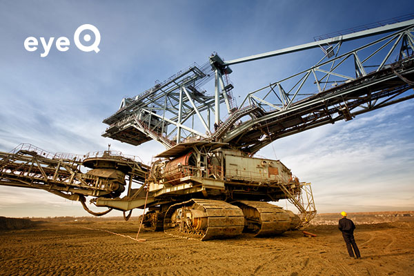 Mine worker standing in front of a huge drill machine