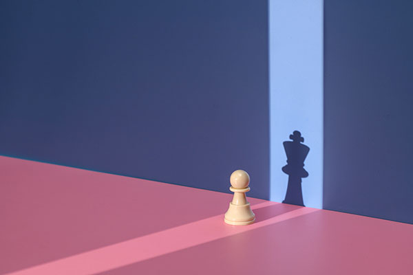 Pawn chess piece with king shadow Getty