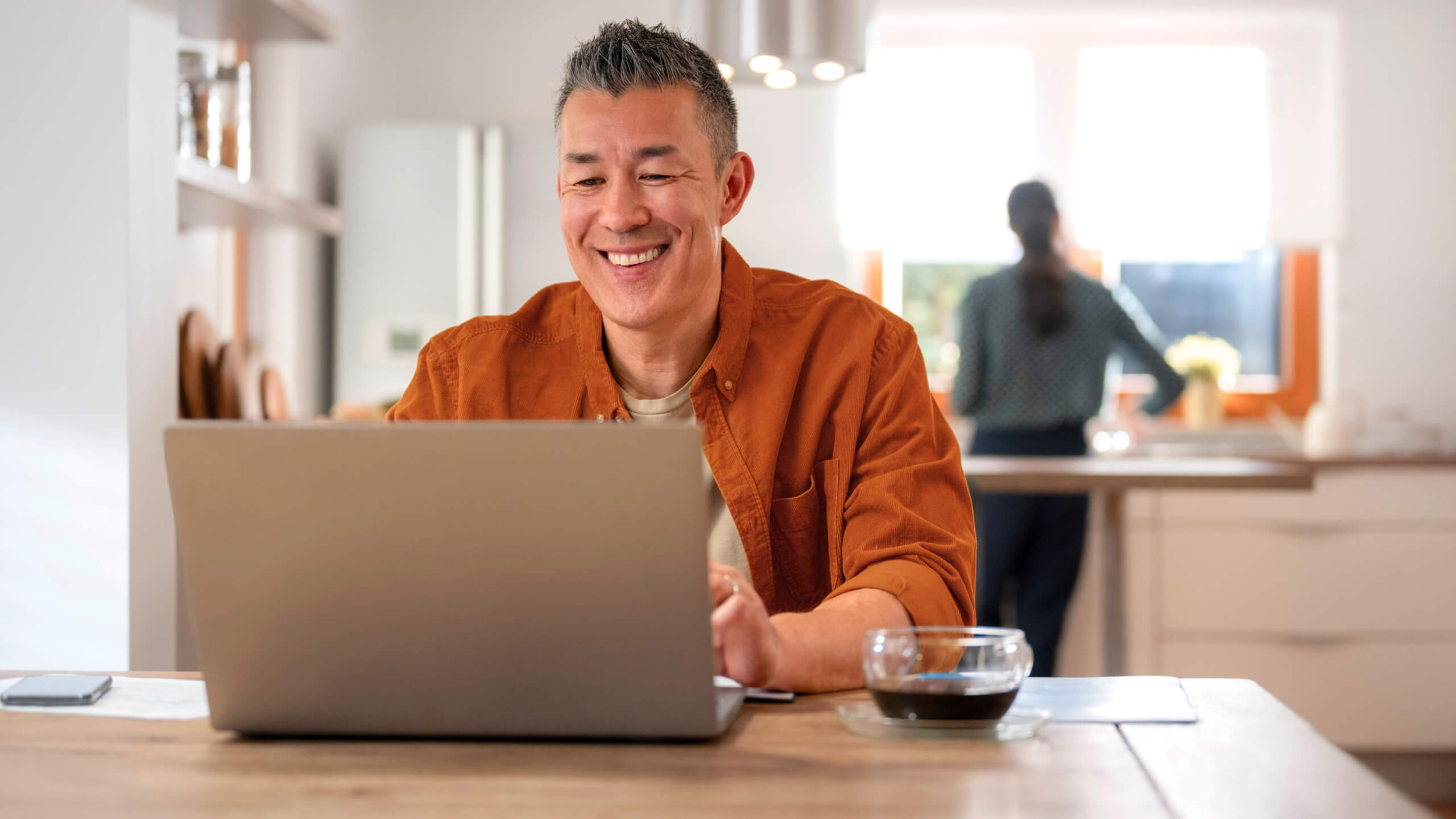 man sat on laptop in kitchen