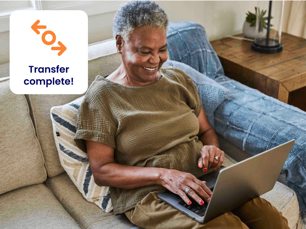 older woman on sofa using laptop to complete transfer