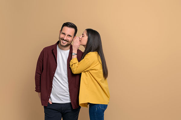 Woman whispering into man's ear