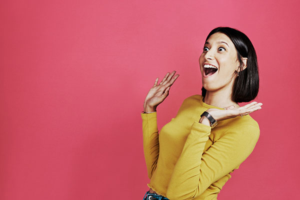 Woman looking surprised against a pink background