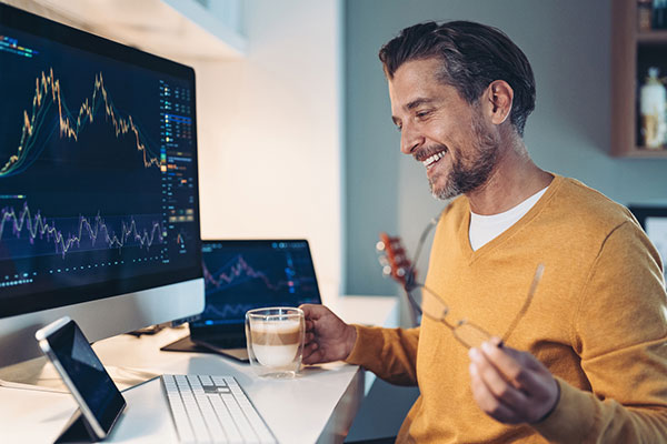 Man smiling and looking at stock exchange graphs