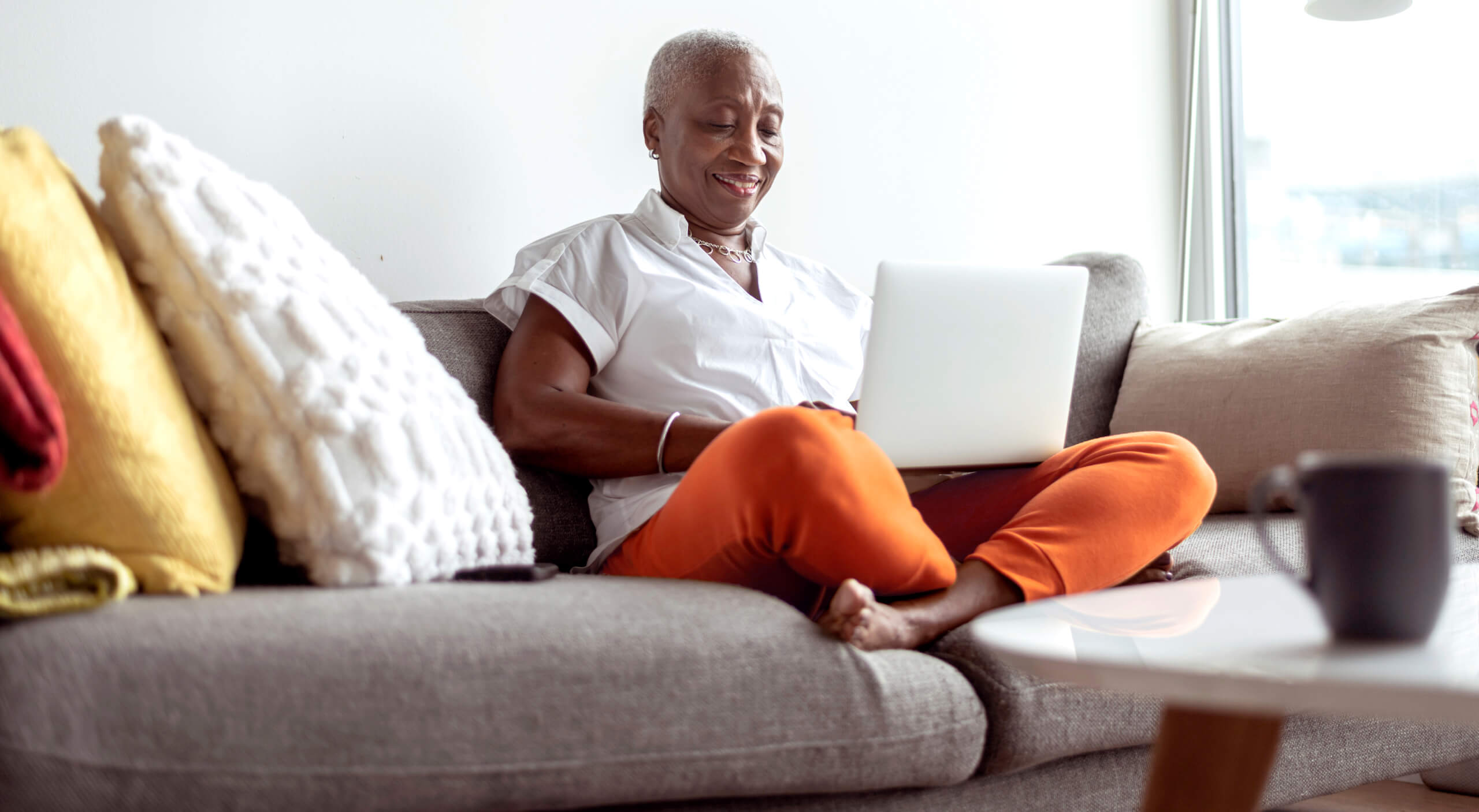 woman using laptop from sofa completing transfers wide shot