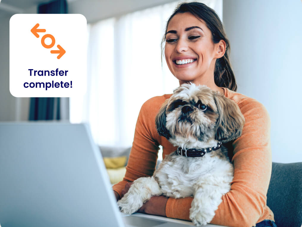 young woman and dog looking happy at laptop transfer completed