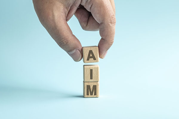 A hand arranging blocks spelling out the word 'AIM'