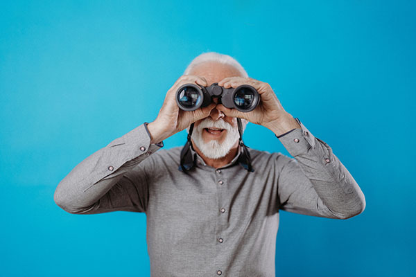 Man looking through his binoculars against a blue background