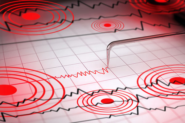 Close-up of a seismograph machine needle tracing seismic waves