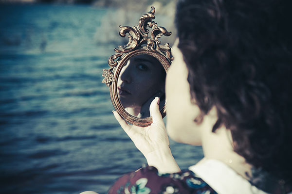 Woman looking into a mirror in her hand