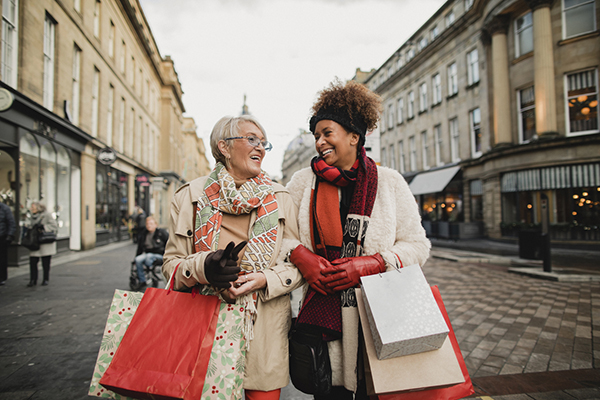 Two women walking through the city streets at Christmas with shopping bags