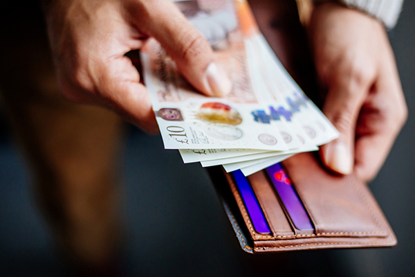 Man holding British banknotes beside his wallet