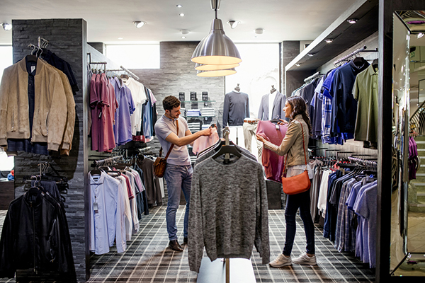 Couple in a clothes store with rails of clothes around them