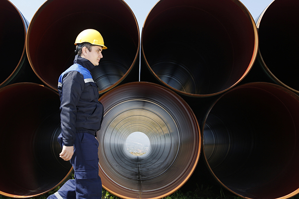 A man walks beside giant pipes