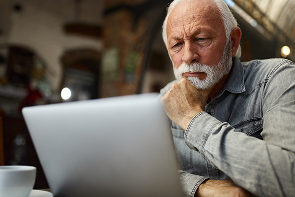 A man looking at his computer screen and thinking about dividends