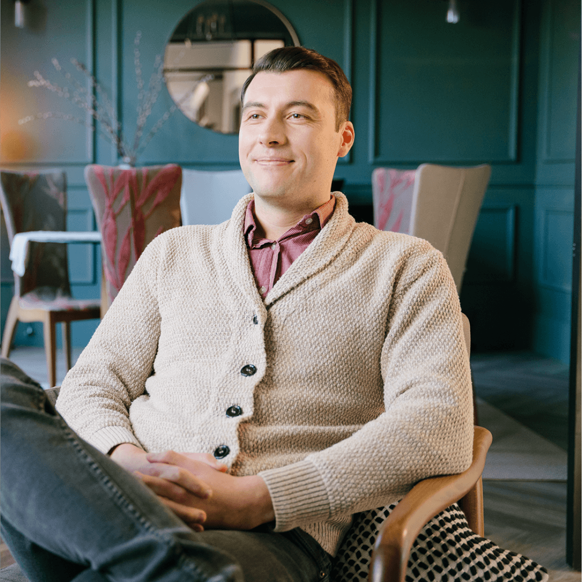 Man sat on a chair smiling to someone out of frame