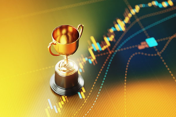 Gold trophy sitting on yellow financial graph 