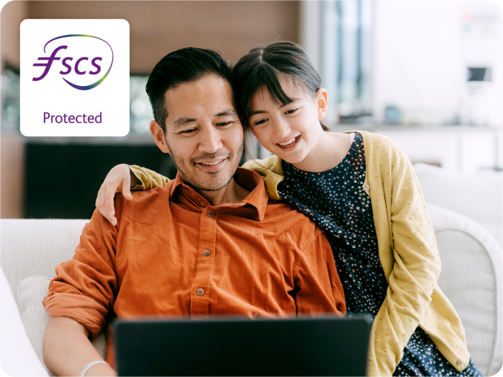 Man and child smile while looking at a laptop. FSCS Protected logo in top left corner.
