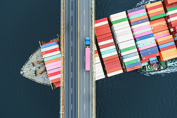 Aerial view of a container ship passing beneath a suspension bridge