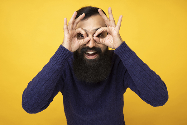 Young man holding fingers up to eyes like binoculars