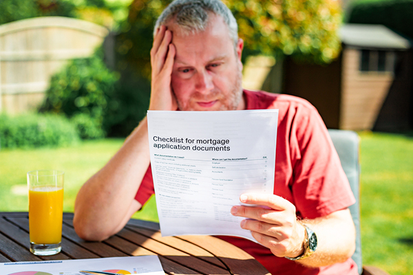A man sitting outside reading mortgage form