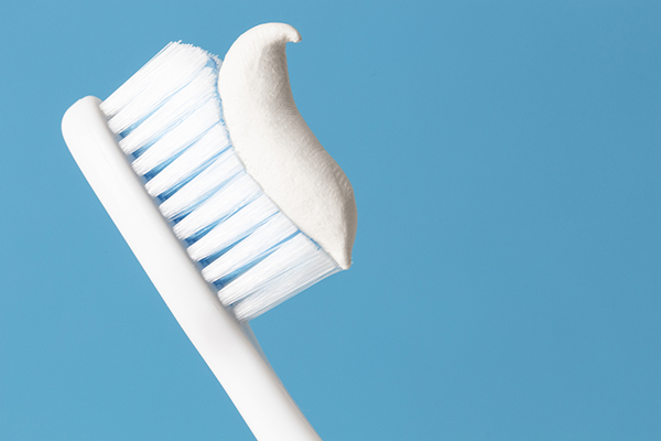 Toothbrush with toothpaste on it against blue background