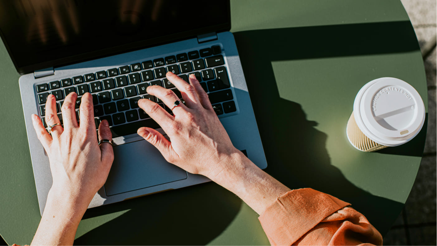 hands checking tax-free cash on laptop with coffee