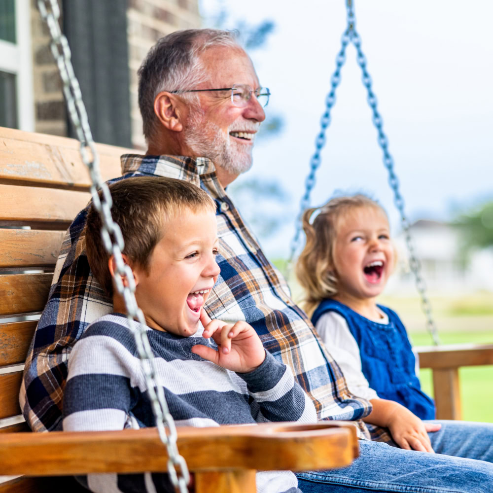 Man outdoors on a bench with grandchildren