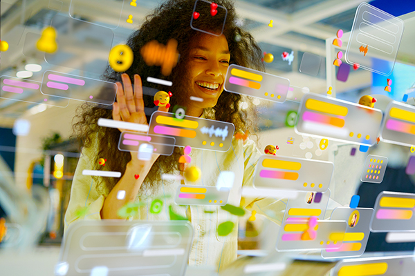 Woman working in office surrounded by multicoloured social media icons and data screens, Getty